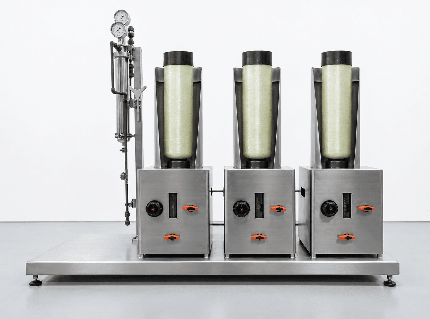 Three-column recovery system on a stainless steel skid, with pale-green columns in open protective shields, orange valve handles on each cabinet, and pressure gauges on the left-hand piping assembly
